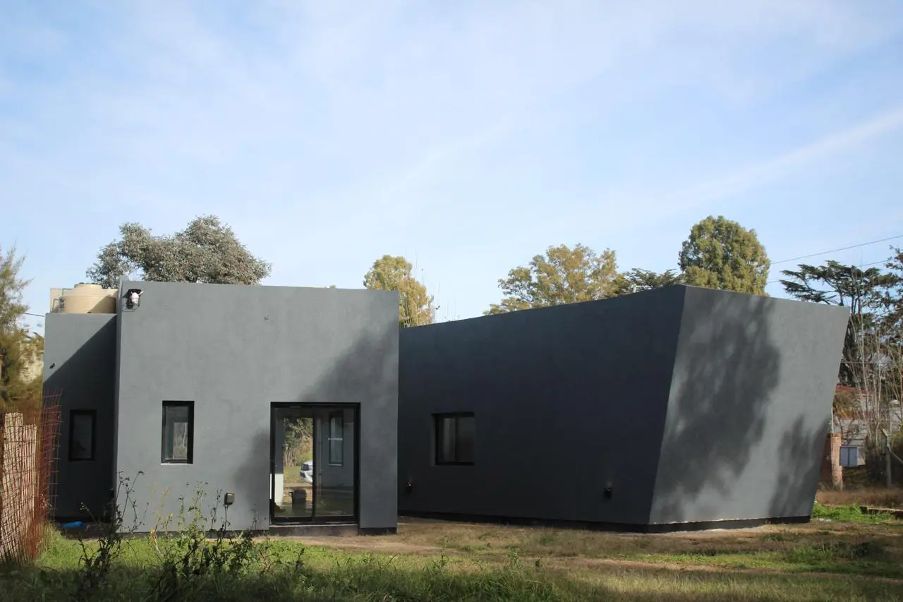 Vivienda de una planta con volúmenes quebrados y terminación exterior oscura